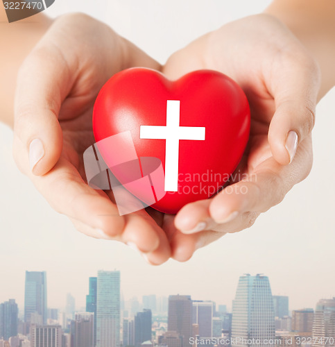 Image of close up of hands holding heart with cross symbol