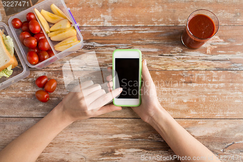 Image of close up of hands with smartphone food on table