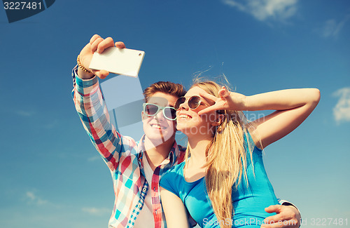 Image of smiling couple with smartphone making selfie