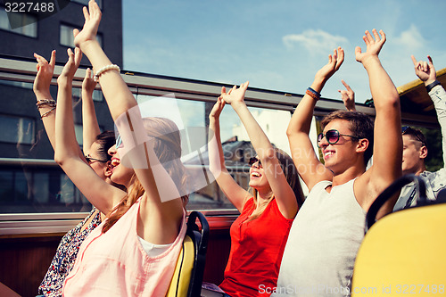 Image of group of smiling friends traveling by tour bus