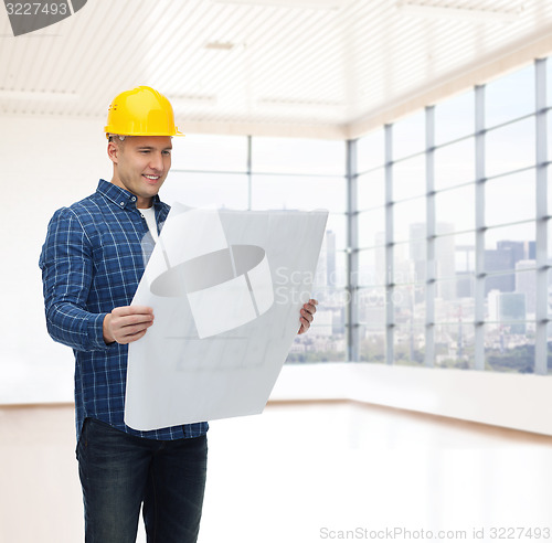 Image of smiling male builder in helmet with blueprint