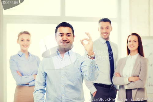 Image of smiling businessman showing ok-sign in office