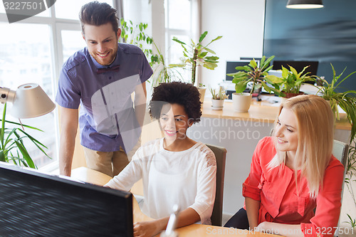 Image of happy creative team with computer in office