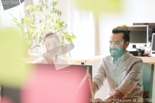 Image of happy creative team with computer in office