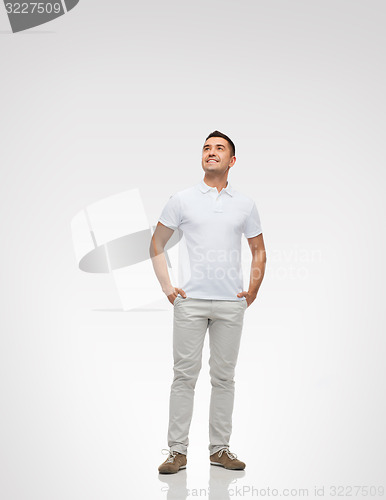 Image of smiling man with hands in pockets looking up