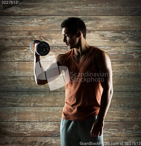 Image of young man with dumbbell flexing biceps