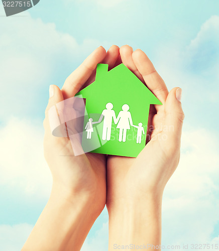 Image of hands holding green house with family