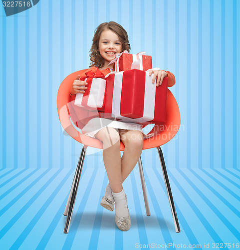 Image of happy little girl with gift boxes sitting on chair