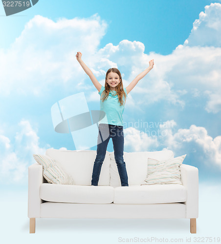 Image of smiling little girl jumping on sofa