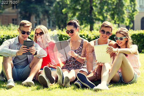 Image of smiling friends with tablet pc computers in park