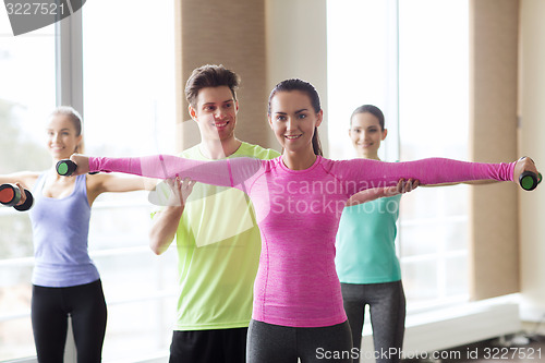 Image of happy women and trainer with dumbbells in gym