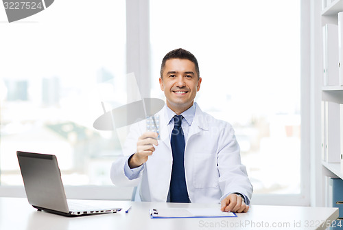 Image of smiling doctor with tablets and laptop in office