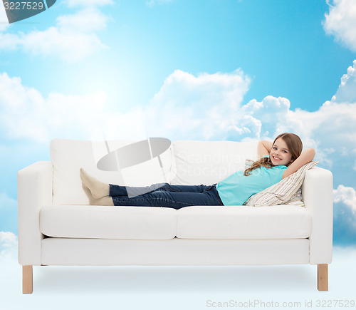 Image of smiling little girl lying on sofa