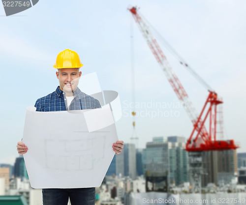 Image of smiling male builder in helmet with blueprint