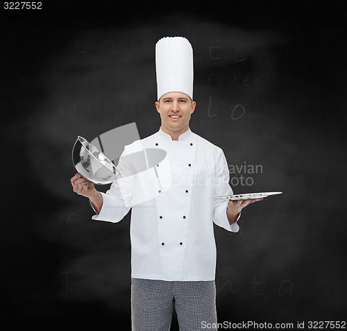 Image of happy male chef cook opening cloche