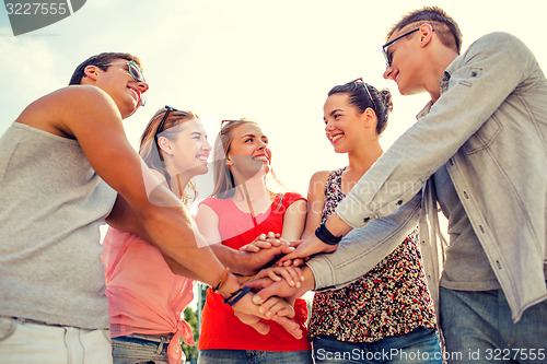 Image of group of smiling friends with hands on top in city