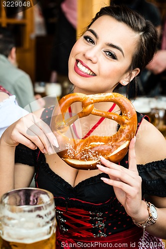 Image of Woman in Dirndl eating Oktoberfest Pretzel