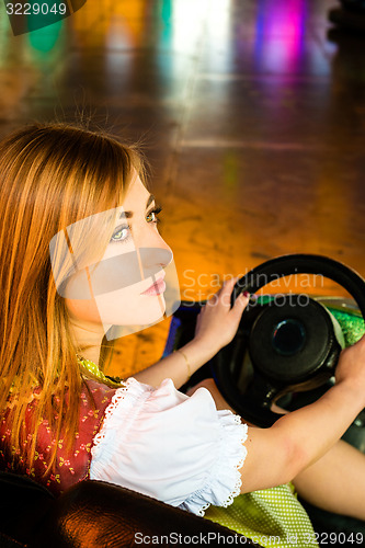 Image of Beautiful girl in an electric bumper car in amusement park