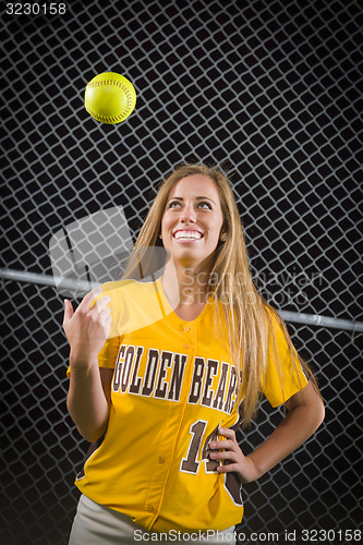 Image of Female Softball Player Portrait with Ball in the Air.