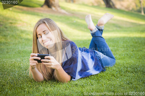 Image of Smiling Young Woman Using Cell Phone Outdoors