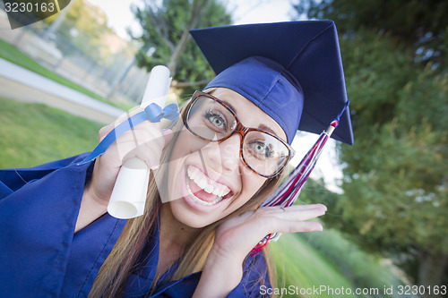 Image of Expressive Young Woman Holding Diploma in Cap and Gown