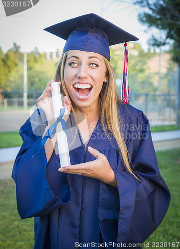 Image of Expressive Young Woman Holding Diploma in Cap and Gown