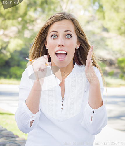 Image of Excited Young Woman With Pencil Outdoors