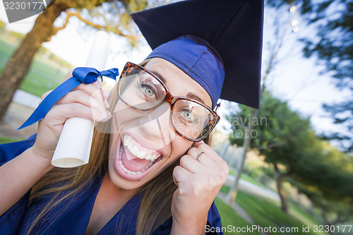 Image of Expressive Young Woman Holding Diploma in Cap and Gown