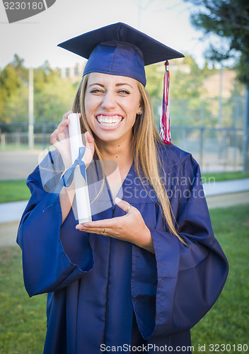 Image of Expressive Young Woman Holding Diploma in Cap and Gown