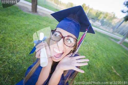 Image of Expressive Young Woman Holding Diploma in Cap and Gown