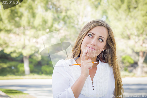 Image of Contemplative Young Woman With Pencil Outdoors