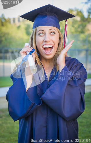 Image of Expressive Young Woman Holding Diploma in Cap and Gown