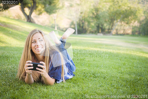 Image of Smiling Young Woman Using Cell Phone Outdoors