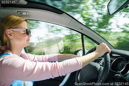 Image of Smiling beautiful woman in sunglass driving car at high speed