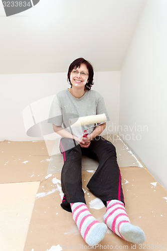 Image of housewife resting after painting wall to white
