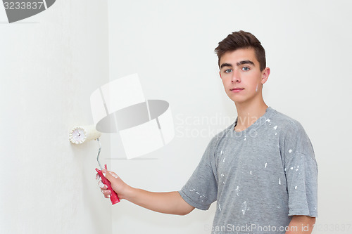 Image of teenager painting wall to white at home