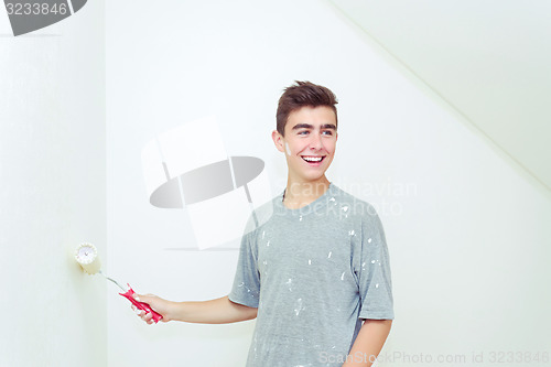 Image of teenager painting wall to white at home