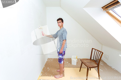 Image of teenager painting wall to white at home