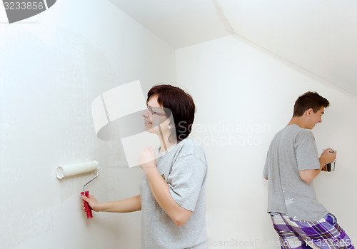 Image of housewife with son painting wall to white