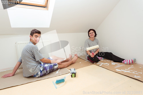 Image of housewife with son painting wall to white