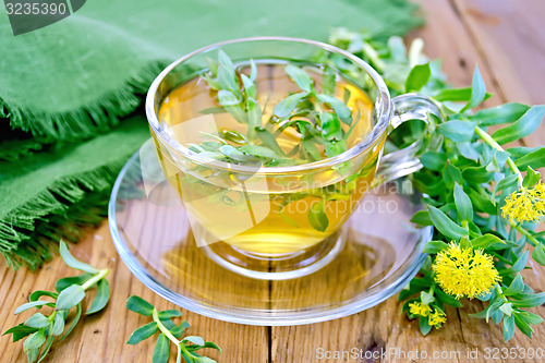 Image of Herbal tea in cup with Rhodiola rosea and napkin on board