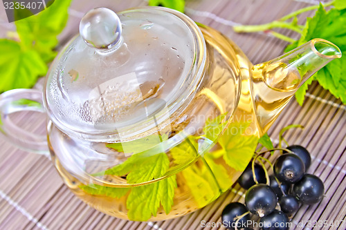 Image of Tea with black currants in glass teapot on bamboo napkin