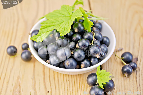 Image of Black currants in bowl with leaf on board