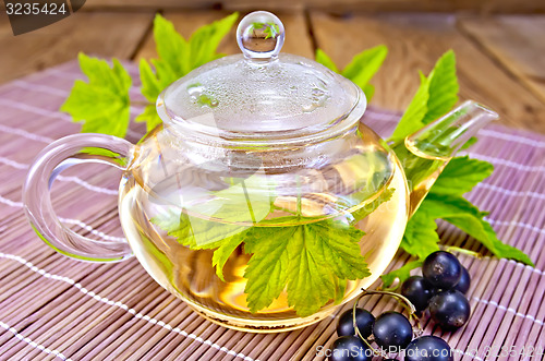 Image of Tea with black currants in glass teapot on board