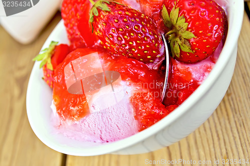 Image of Ice cream strawberry in bowl with spoon on board