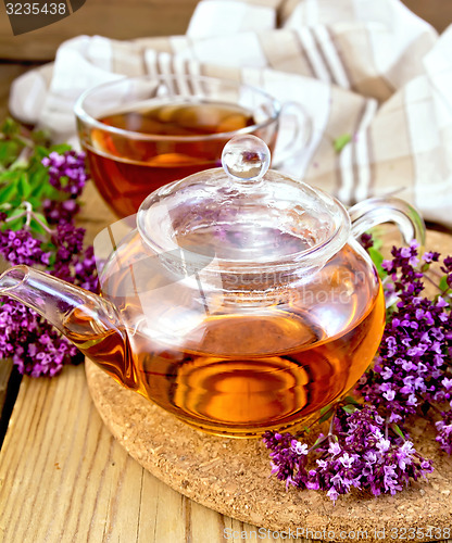 Image of Tea from oregano in glass teapot and cup on board