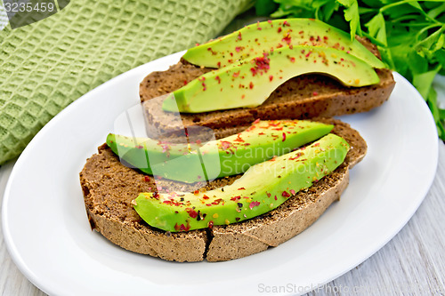 Image of Sandwich with avocado and pepper in bowl on light board