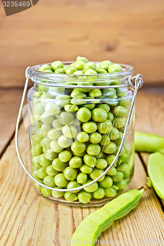 Image of Green peas in glass jar on wooden board
