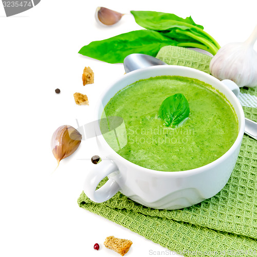 Image of Soup puree with croutons and spoon in bowl on napkin