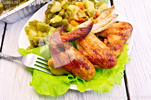 Image of Chicken wings fried with vegetables and salad in plate